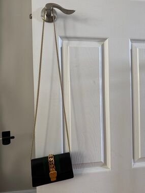 Black Crossbody Bag with Gold Chain Accent and Green Stripe